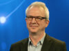 Xintela's chairman Gregory Batcheller in BioStock's studio against a blue background with white dots