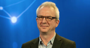 Xintela's chairman Gregory Batcheller in BioStock's studio against a blue background with white dots