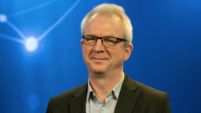 Xintela's chairman Gregory Batcheller in BioStock's studio against a blue background with white dots